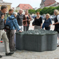 Ein Stadtführer zeigt den Touristen das historische Denkmal am Neustädtischen Markt